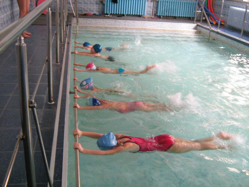 Деца в басейн се учат да плуват
